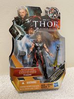 Front view of sealed 2011 Thor action figure in packaging, includes battle hammer and sword accessories visible.