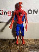Front view of the Spiderman figure standing upright on a marble surface against a wall with Kings ON sign