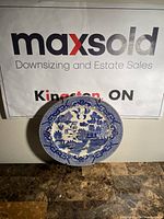 Front view of the blue and white Japanese ceramic plate showing detailed traditional landscape design with pagodas, trees, birds, and water.