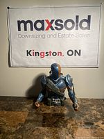 Front view of the Deathstroke bust figure on a table with MaxSold banner behind