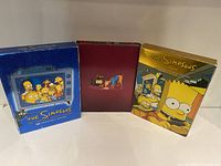 Three DVD sets for The Simpsons Seasons 9, 10, and 14 in colorful slipcases showing the Simpsons family on the front.