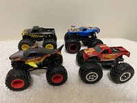 Four Hot Wheels Monster Trucks together showing various colors and designs