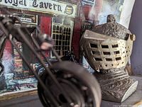 Side angle showing the detailed engravings and profile of the medieval helmet shaped lighter, with movable face guard mechanism visible.