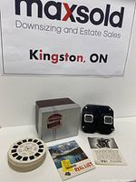 Overall lot contents showing metal box, 36 view reels, black stereoscope, and paperwork