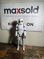 Front view of white Stormtrooper action figure standing on tabletop against a MaxSold banner.