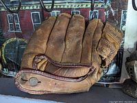 Brown vintage baseball glove laid flat showing fingers, thumb padding, and visible wear.