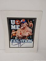 WWE promotional picture of John Cena signed by him with multiple images of Cena in action and 'U CAN'T SEE ME' and 'CENATION' text.