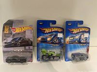 Lot of three Hot Wheels toy cars in sealed packaging shown side by side