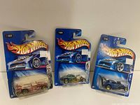 Photo of three Hot Wheels cars in original blister packaging, showing front view and packaging logos and numbers.