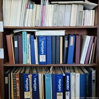 Three shelves filled with various flight safety manuals, flight operation binders, and assorted paperwork in binders and folders.
