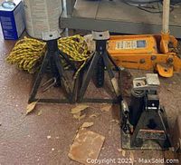 Hydraulic floor jack, two jack stands, rope arranged on floor showing condition and details.