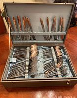 Cutlery neatly arranged in lined box showing knives on top section and forks and spoons in bottom section