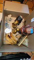 Overview of box contents showing mixed decorative figures, dried corn, candle, plaques and rock specimen.