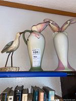 Shelf display of two vases and bird figurine showing overall condition and scale on bookshelf