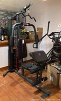 Angled front view of assembled Marcy home gym unit on hardwood floor showing weight stack and press arms