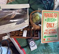 Wooden box with rock collection, Star Wars poster, basket with tennis balls, Irish parking sign, and tarot cards on a green surface.