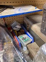 Photo of the dusty metal tool box and small plastic boxes containing nails and screws on a workshop pegboard shelf.