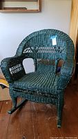 Front view of green wicker rocking chair showing woven seat, back, armrests and rocker base.