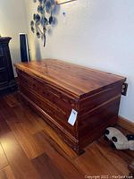 Full side view of closed wooden chest showing natural wood finish and rectangular shape.