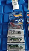 Four Hot Wheels cars in original blister packs arranged vertically in a blue container.
