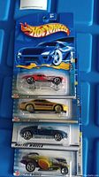 Four unopened Hot Wheels cars in packaging, including red Corvette, gold car, blue car, and green car, each sealed on blue Hot Wheels card.