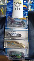 Four unopened Hot Wheels cars displayed vertically in original packaging showing various models and design details.