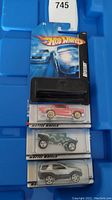 Four unopened Hot Wheels cars in original packaging with mystery bases. Red, green, silver, and grey cars visible.