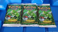 Three sealed booster packs side by side on blue tray