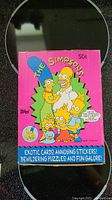 Front-facing photo showing Simpsons family illustration on vintage pink box for Topps cards.