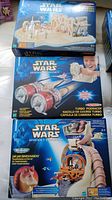 Top-down photo showing three boxed Star Wars Episode I collectible play sets including the desert scene set, Turbo Podracer, and Jar Jar Binks/Naboo action set