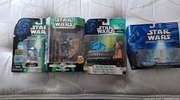 Four Star Wars Episode I collectible figures in original packaging including R2-D2, Boba Fett, Max Rebo Band, and Micro Machines set
