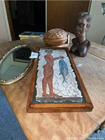 Photo showing all four items on wooden table: signed mosaic, wooden bust, oval mirror, and wooden nut dish.