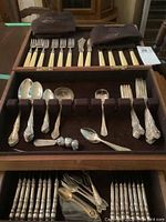 Wooden canteen open showing top tray with eight bone-style handled Birks forks and felt storage bags plus lower tray with sterling spoons, spreaders and gravy ladle