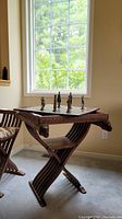 Full view of carved wood chess table with removable chessboard top and metal pieces on top