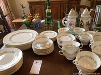 Wide view of the 8 piece place setting showing plates, cups, saucers, and creamed soup bowls with two chips visible on soup bowls.