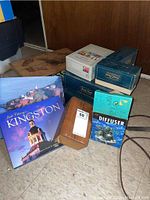 Wide view of all items in the lot showing game boxes, books, diffuser, and wooden Bridge box.