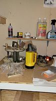 Top of workbench including yellow flashlight, bolt cutters, propane tank with soldering hardware, and various small containers and bottles.
