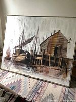 Full view of framed painting leaning against wall on patterned rug