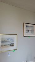 Two framed prints on wall, one larger white matted with gold frame and one smaller black matted with gold frame.