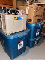 Three plastic storage bins stacked containing various tools and hardware supplies.