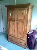 Front view of the solid pine wardrobe showing two paneled doors and bottom dovetailed drawer with metal handles.