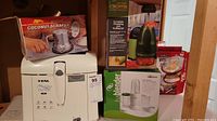 Photo showing all items in the lot: T-fal deep fryer, Aristocrat coconut scraper in box, chopping and grating set, and Isablender boxed set.