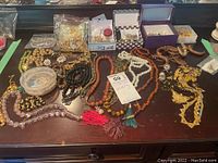 Full view of various costume jewelry items including necklaces, earrings, and rings spread on a table surface.