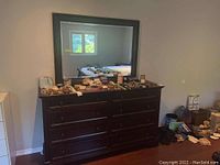 Front view of wood dresser with eight drawers and large mirror attached, showing dark finish and drawer hardware.