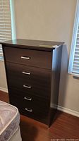 Front view of dark wood dresser with 5 drawers and silver metal handles.