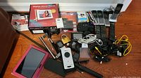 View of entire electronics lot showing boxed digital photo frame, cordless phone sets, cords, calculators, and lock.