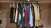 Wide view of ladies clothes hanging on a rack showing a variety of colors and patterns.