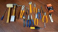 Top view of entire tool assortment laid out showing rubber mallet, claw hammer, pliers, wrenches, screwdriver and utility knife