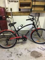Full side view of the black and red SanPedro SuperCycle 6-speed adult bike in garage, showing the frame, tires, seat, and pedals.