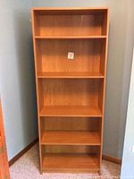 Front view showing five open shelves in a light to medium brown wood finish.